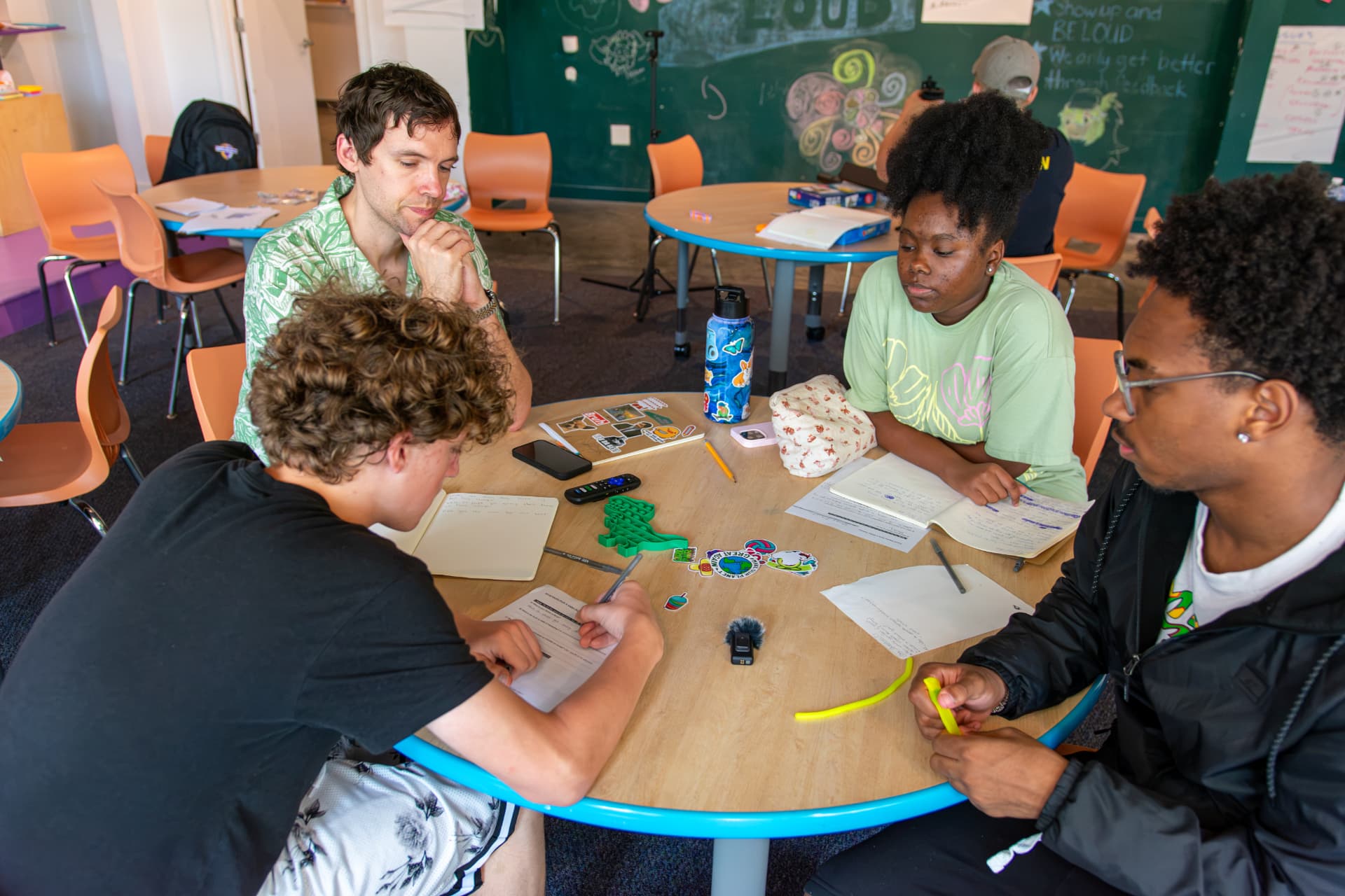 Youth and mentors discussing story ideas around a studio table