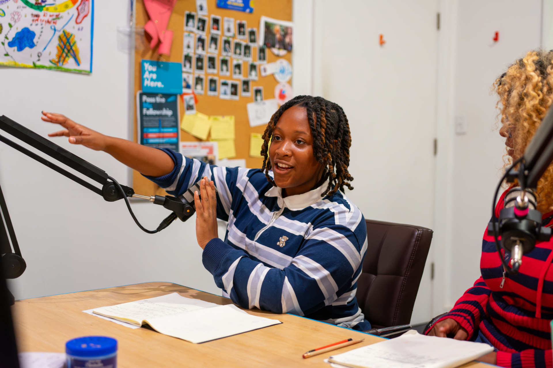 A student gesturing while speaking into a studio microphone
