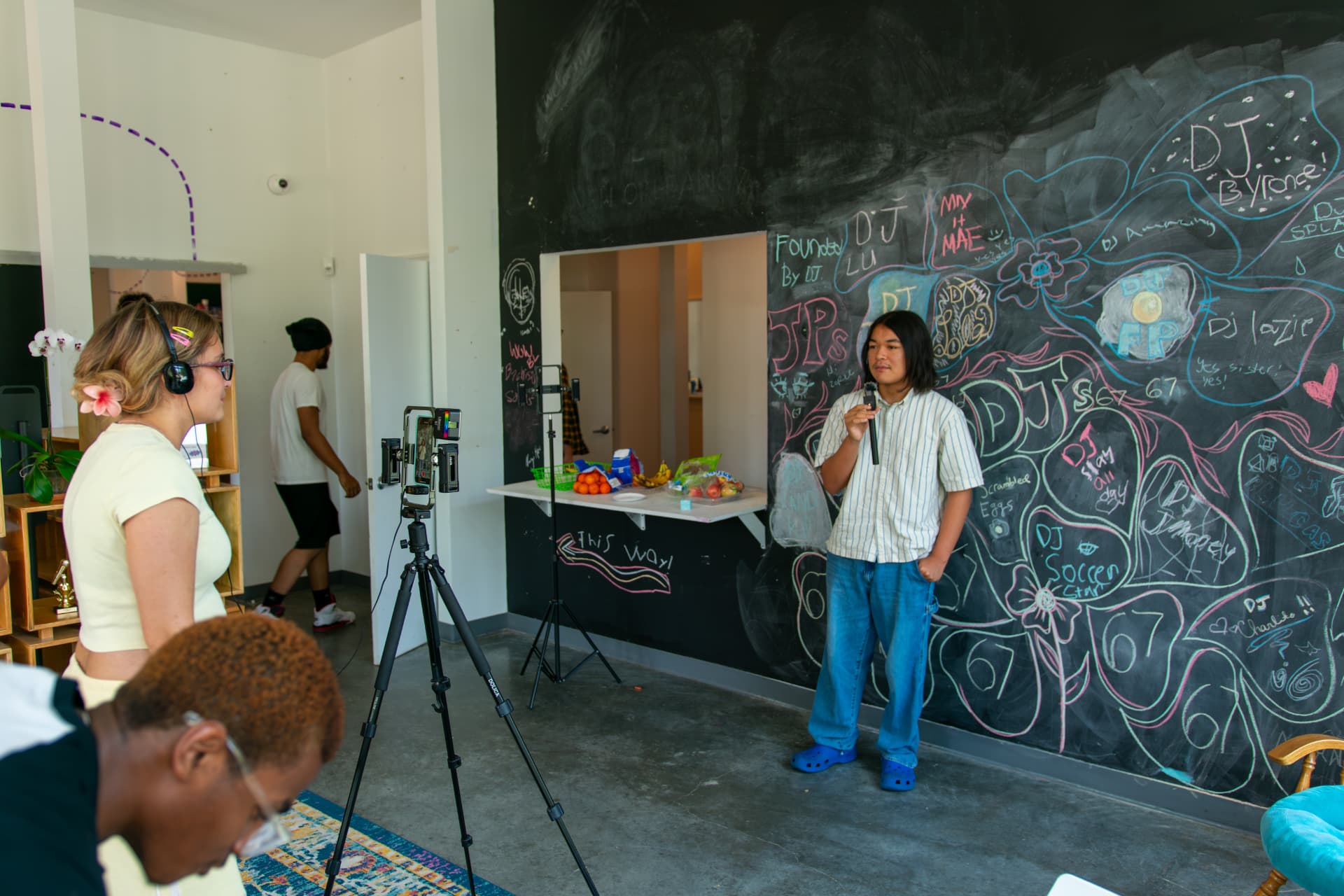 A young person recording in front of the Be Loud chalk wall